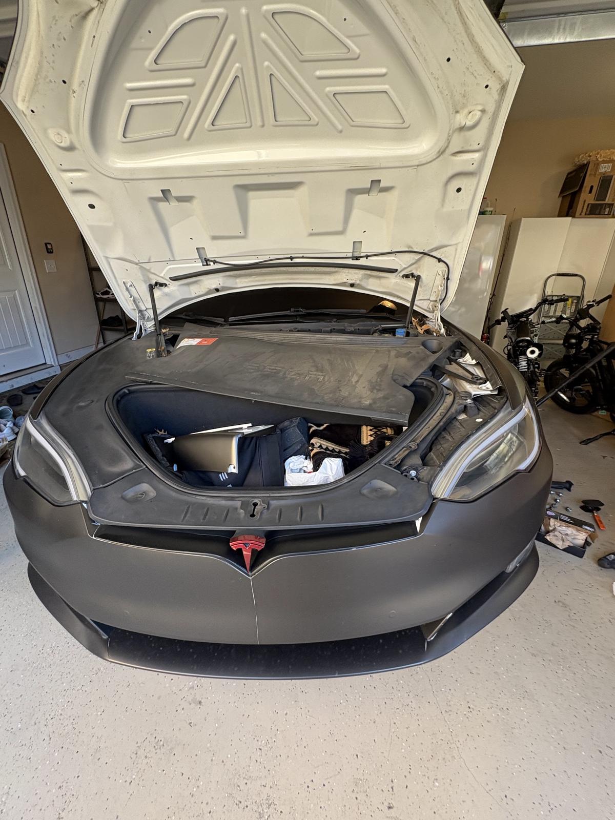 Electric sedan with the front trunk open in a home garage