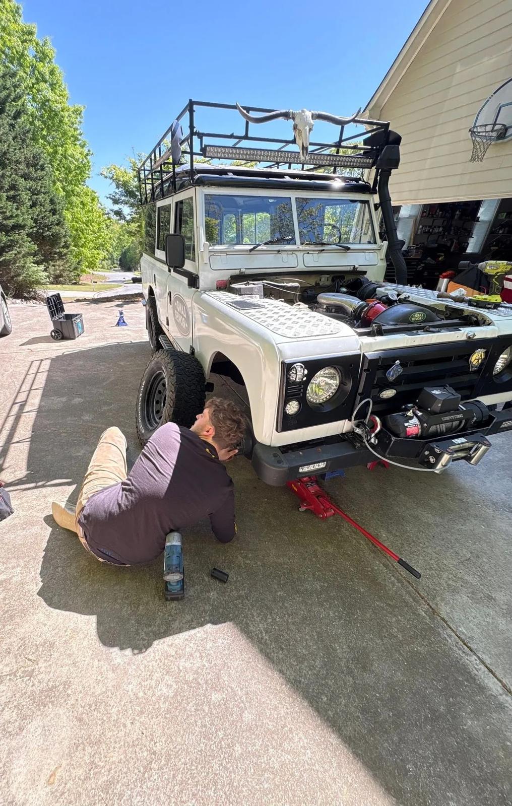 Working under a white classic four-by-four in a driveway