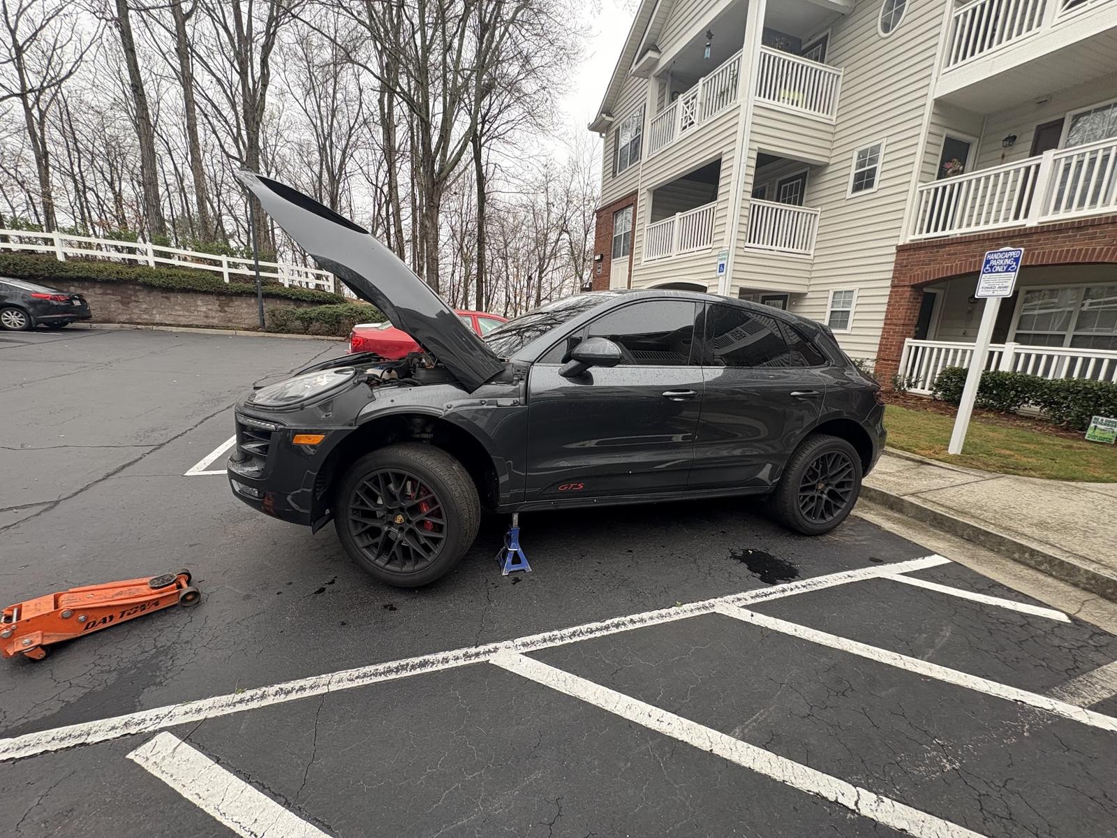 Black SUV raised on jack stands in an apartment parking lot