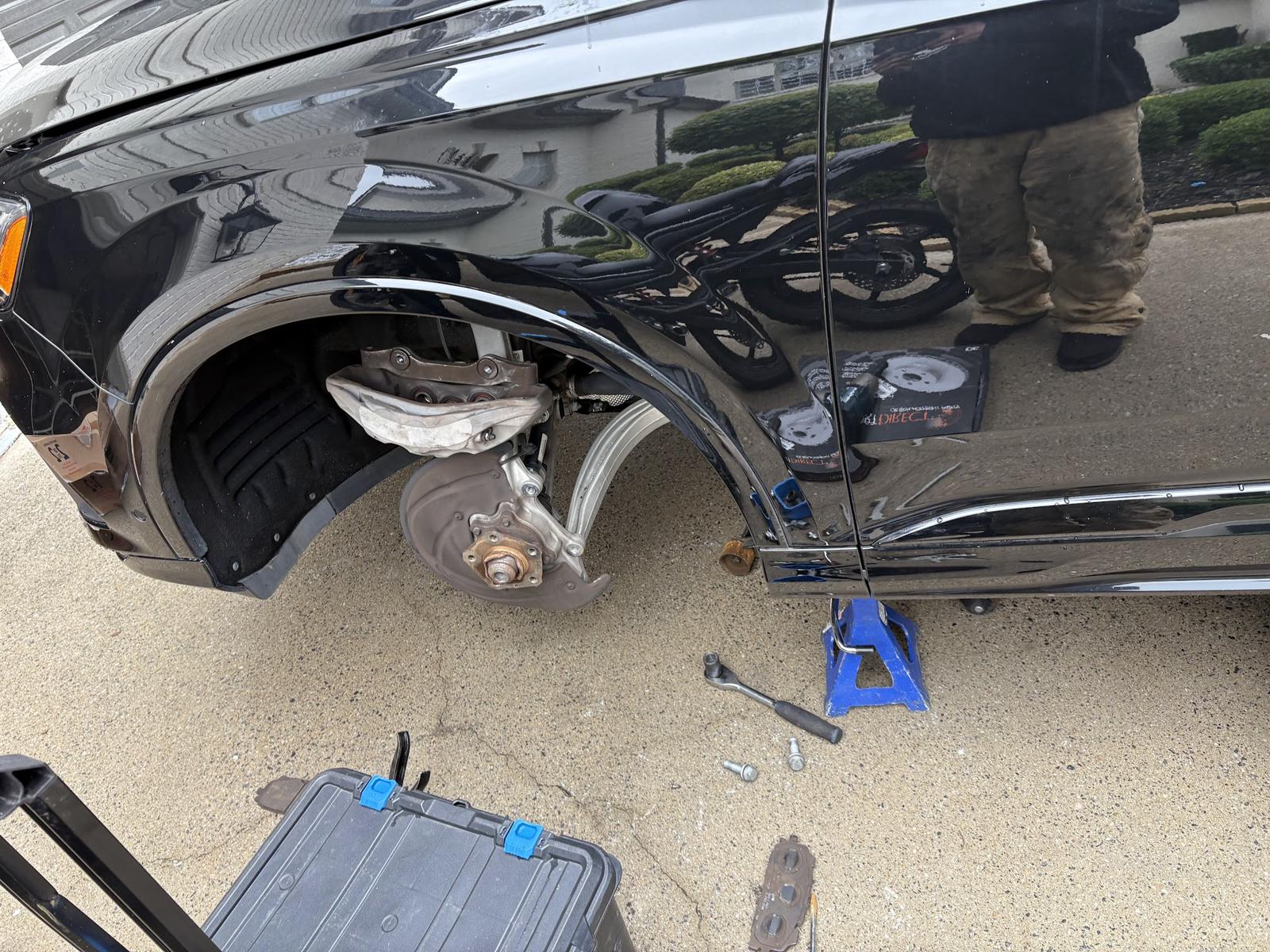 Front corner of a car with the wheel off and the tool case open